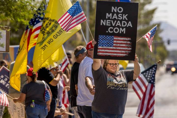 Supporters hold signs and flags during the No Mask Nevada rally to oppose the face mask mandate ...