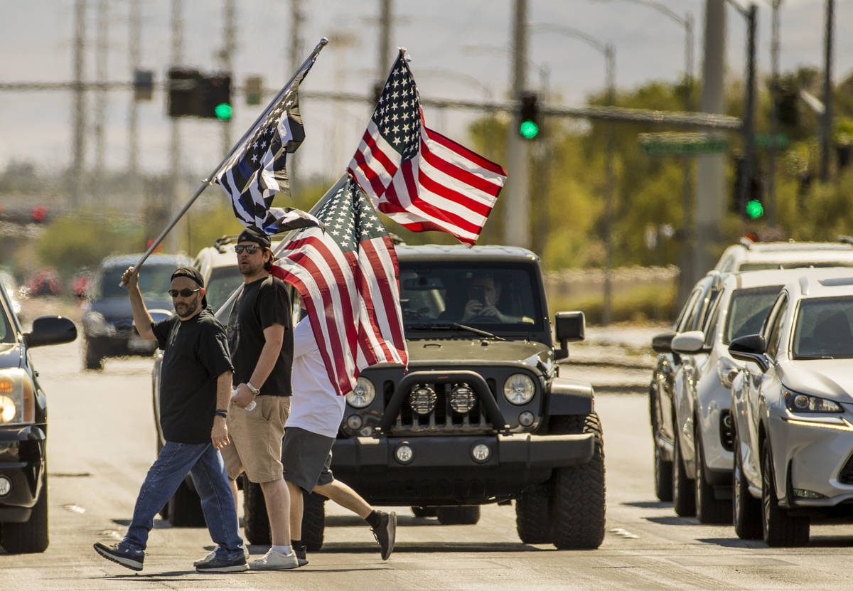 Supporters carrying flags make another cross of traffic during the No Mask Nevada rally to oppo ...