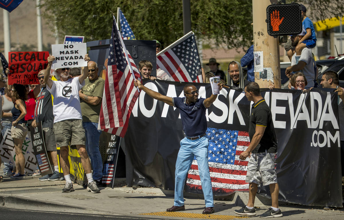 Mack Miller, center, is greeted by Proud Boy Anthony Mastrostefano, right, during a No Mask Nev ...