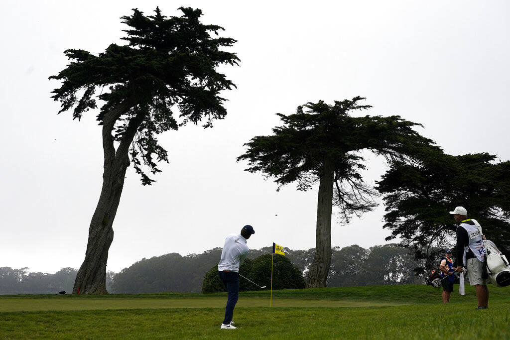Scottie Scheffler chips to the green on the 18th hole during the third round of the PGA Champio ...