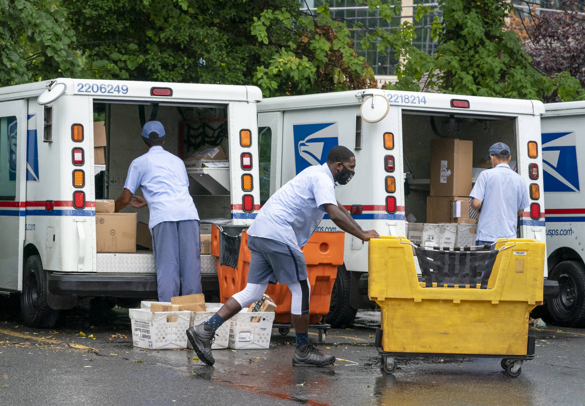 FILE - In this July 31, 2020, file photo, letter carriers load mail trucks for deliveries at a ...