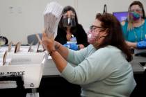 Miami-Dade County Department of Elections employee Elizabeth Prieto gathers vote-by-mail ballot ...