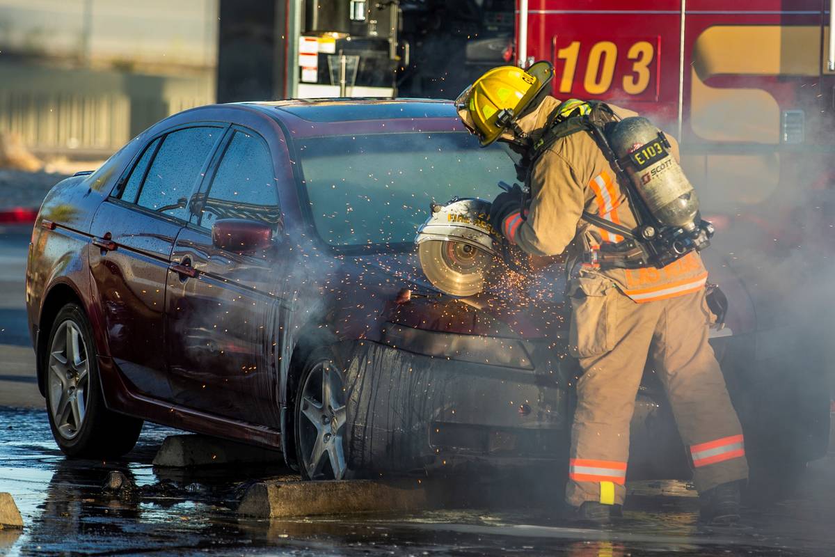 A Las Vegas Firefighter saws open the hood of a vehicle to fight a car fire in the Mariana's Su ...