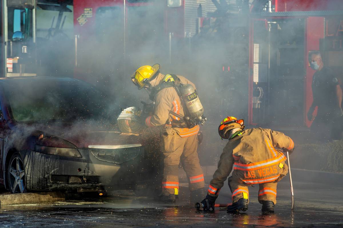 A Las Vegas Firefighter saws open the hood of a vehicle to fight a car fire in the Mariana's Su ...