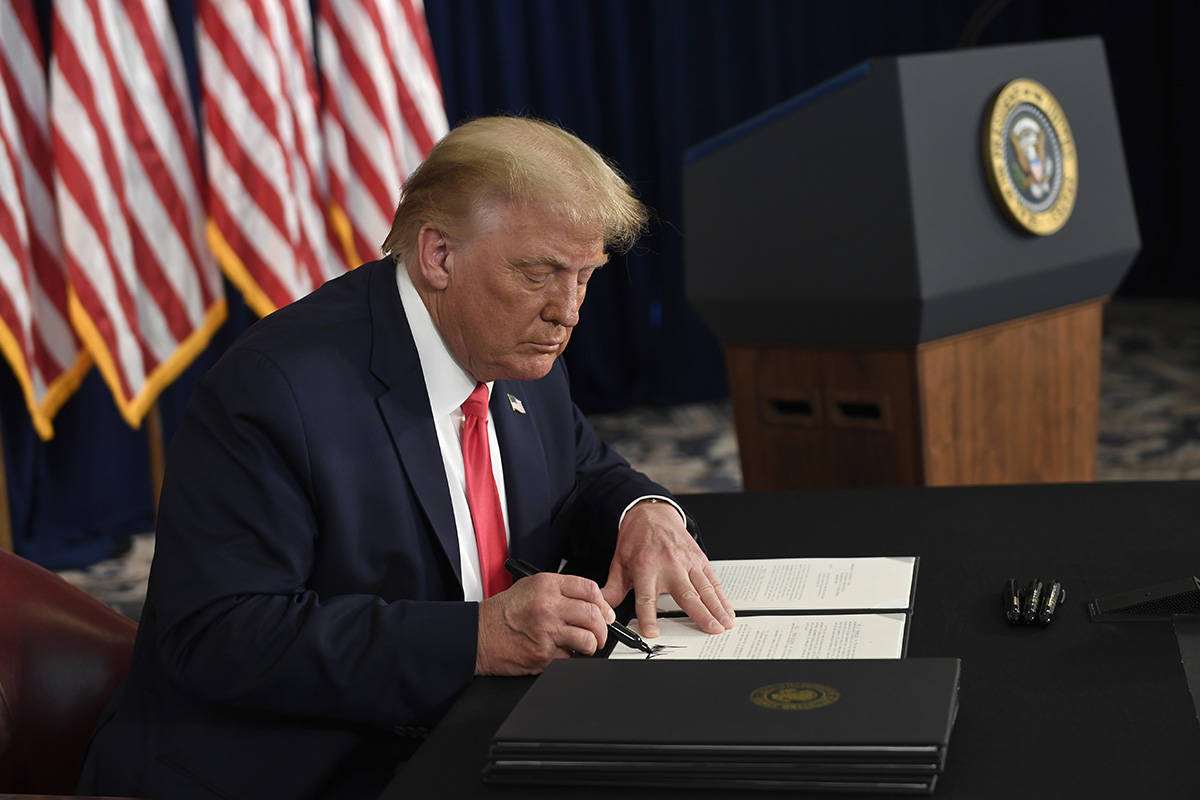 President Donald Trump signs one of four executive orders addressing the economic fallout from ...