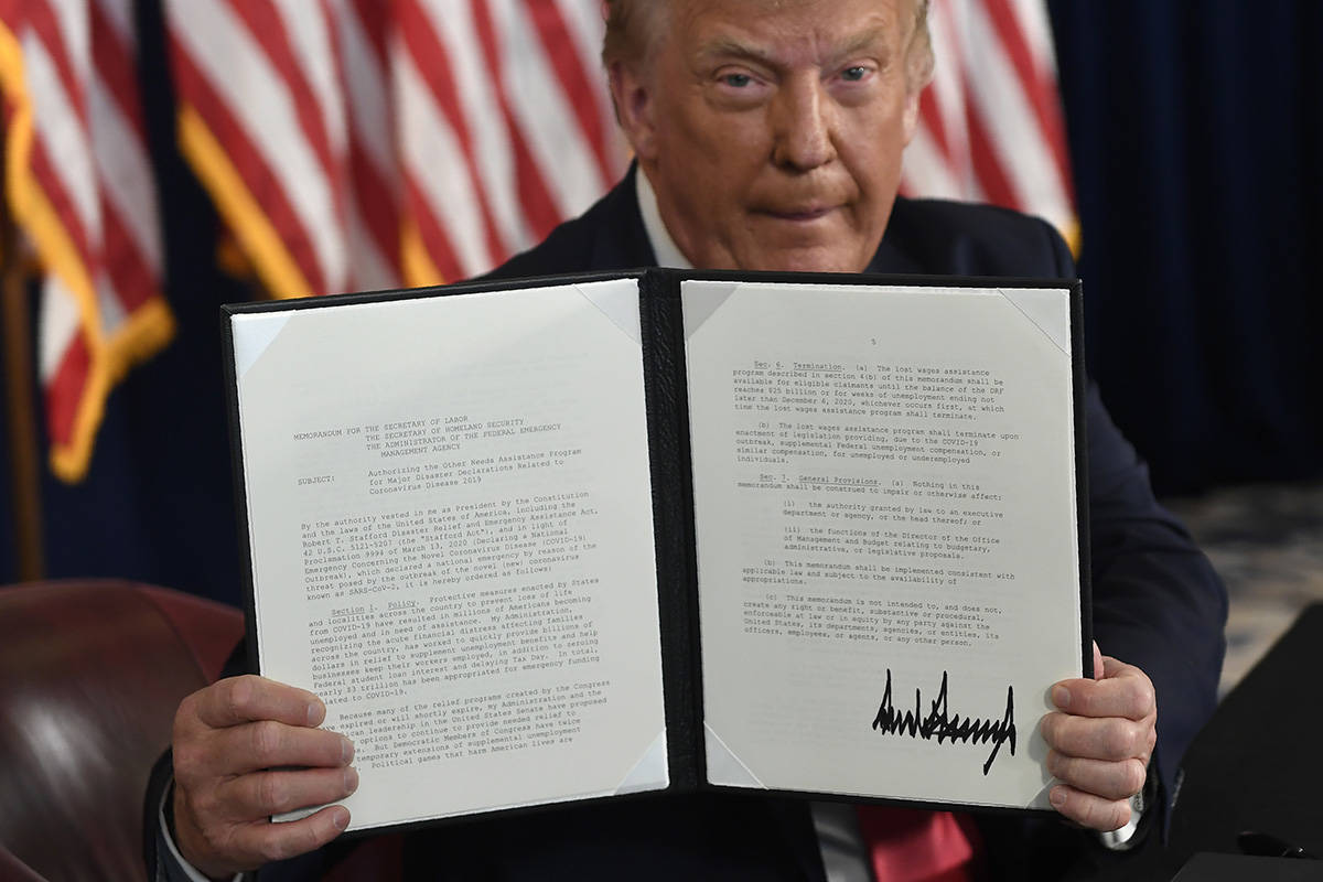 President Donald Trump hold up one of the four executive orders that he signed that addresses t ...