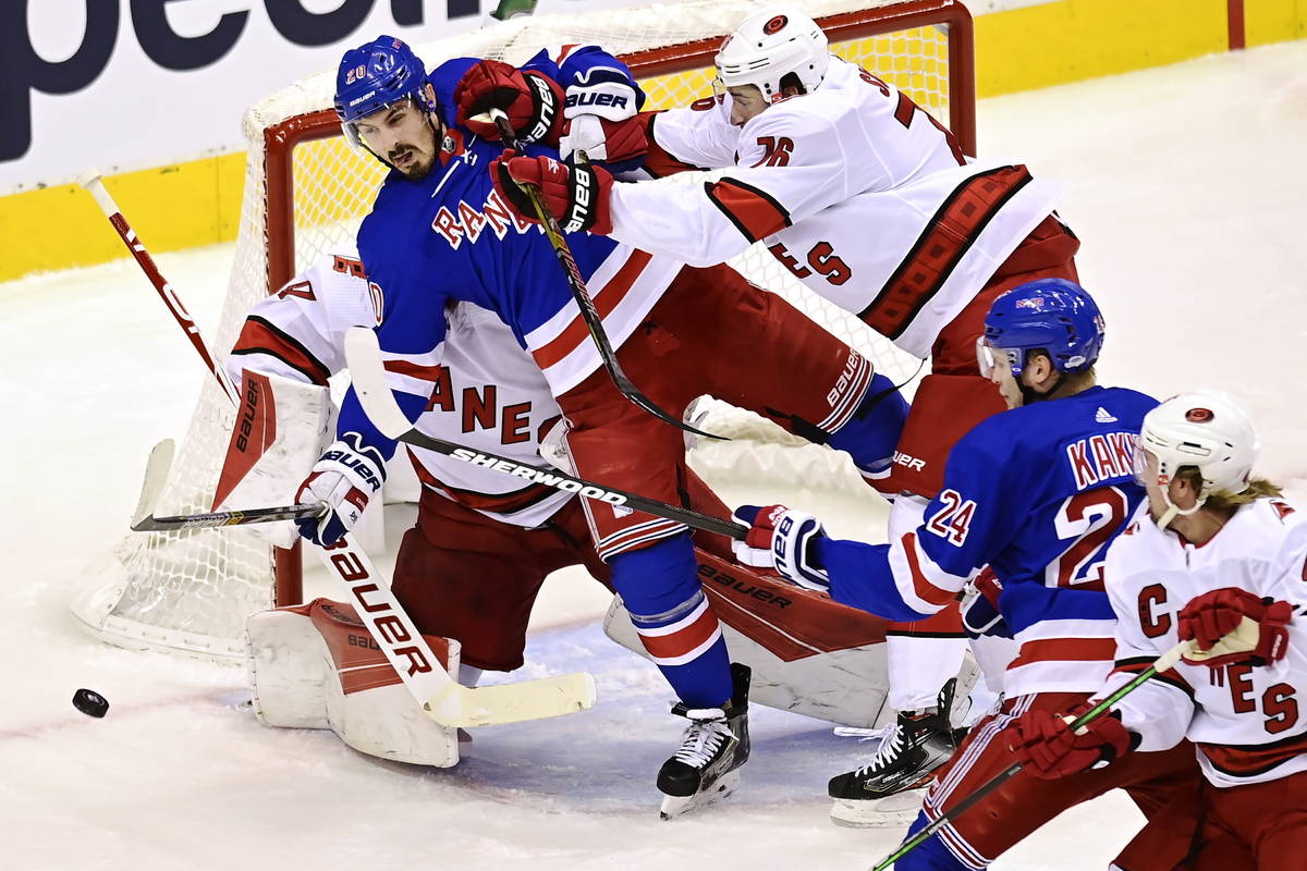 New York Rangers' Chris Kreider (20) is hit by Carolina Hurricanes' Brady Skjei (76) in front o ...