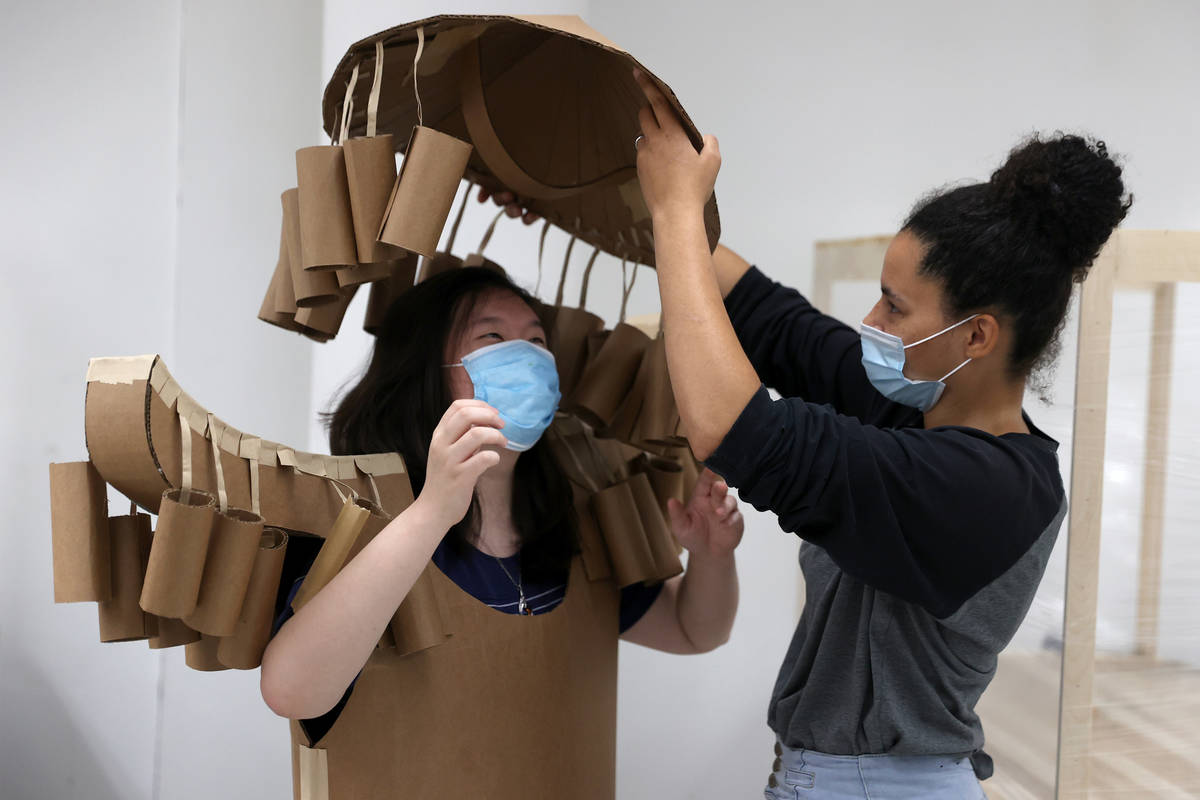 Jessica Yi, left, gets help with putting on a cardboard costume from Tabiya Conyers, during the ...