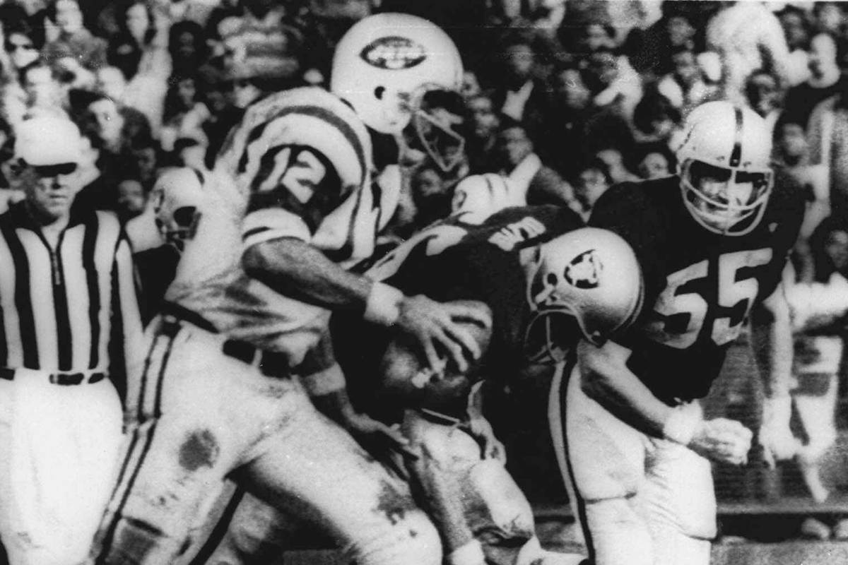 New York Jets' quarterback Joe Namath (12) sweeps around the right side past Oakland defenders ...