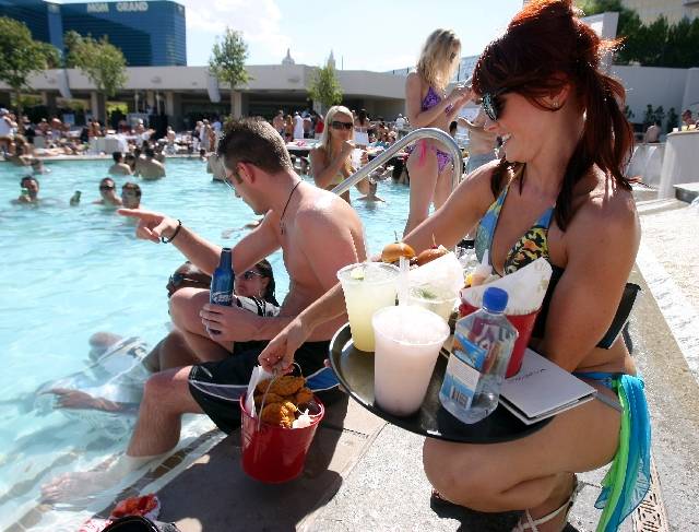 A cocktail server brings drinks and food to customers at the Wet Republic adult pool and beach ...