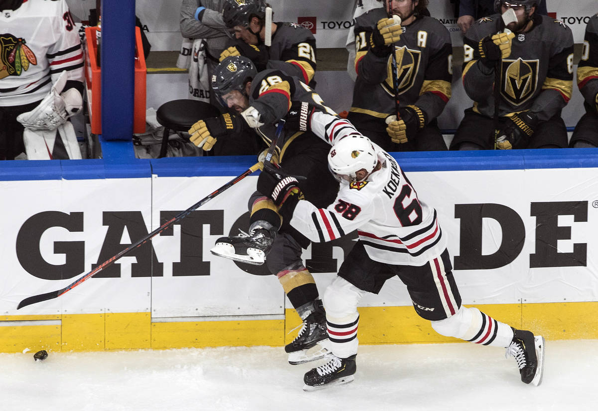 Vegas Golden Knights' William Carrier (28) is checked Chicago Blackhawks' Slater Koekkoek (68) ...