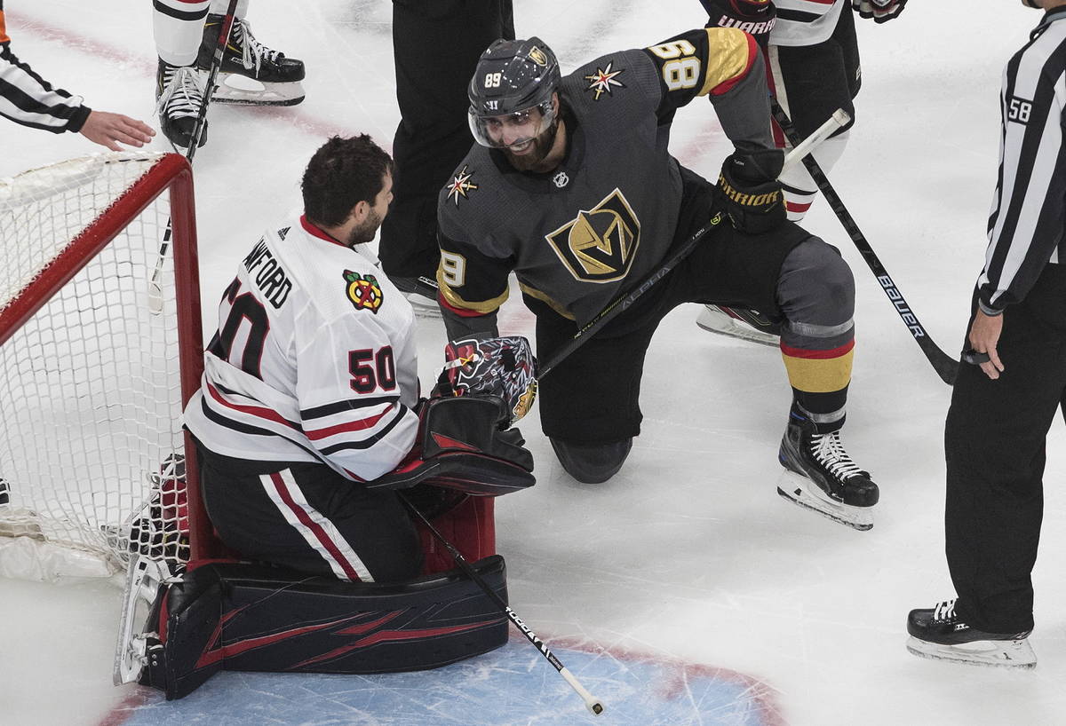 Vegas Golden Knights' Alex Tuch (89) and Chicago Blackhawks goalie Corey Crawford (50) have a l ...