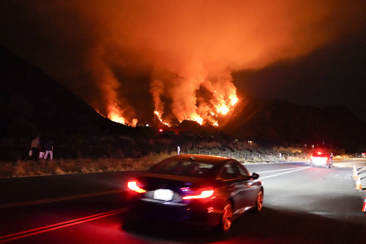 Motorists make their way along a road as the Ranch Fire burns, Thursday, Aug. 13, 2020, in Azus ...