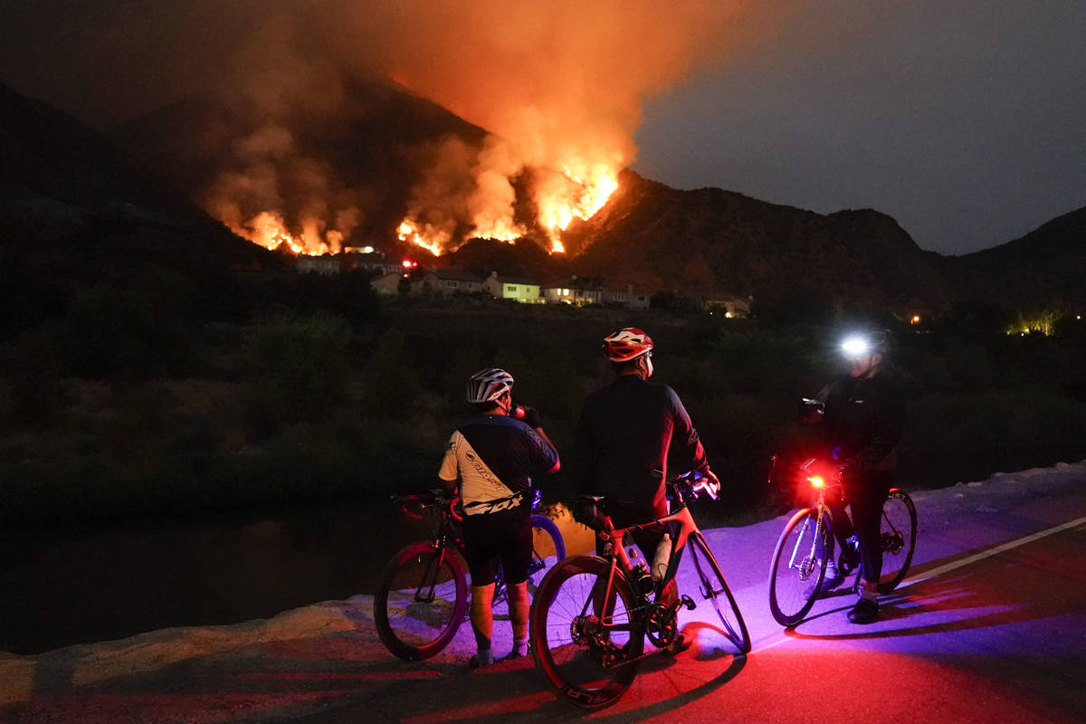 Cyclists rest along a trail as the Ranch Fire burns, Thursday, Aug. 13, 2020, in Azusa, Calif. ...