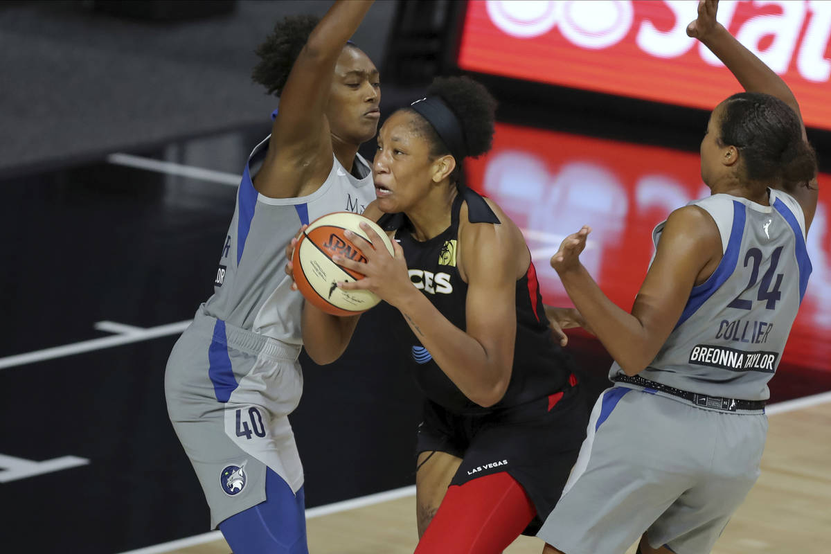 Las Vegas Aces' A'ja Wilson drives between Minnesota Lynx's Kayla Alexander (40) and Napheesa C ...