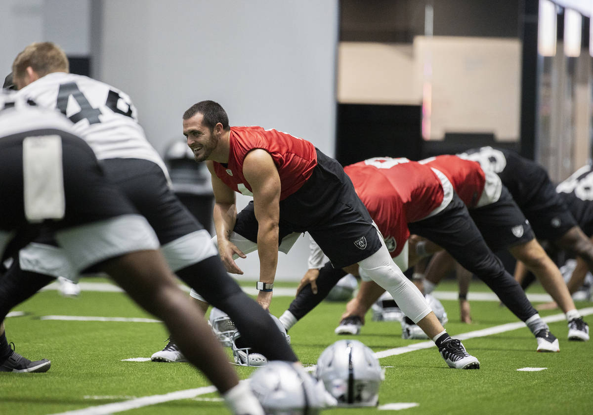 Raiders quarterback Derek Carr, middle, jokes around with teammates while stretching during an ...