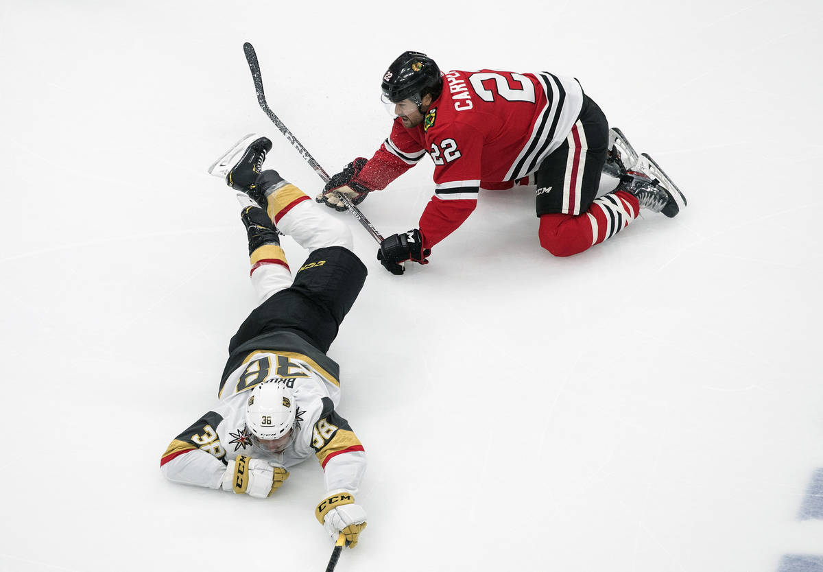 Vegas Golden Knights' Patrick Brown (38) is tripped up by Chicago Blackhawks' Ryan Carpenter (2 ...