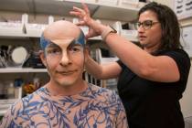 Performer and coach Didier Antoine, left, gets his makeup applied to play the role of Morpheus ...