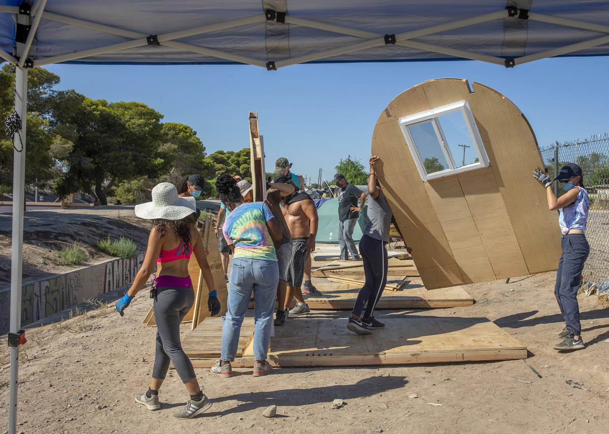 Members of Food Not Bombs and the Sidewalk Project set in place prefabricated pieces to constru ...