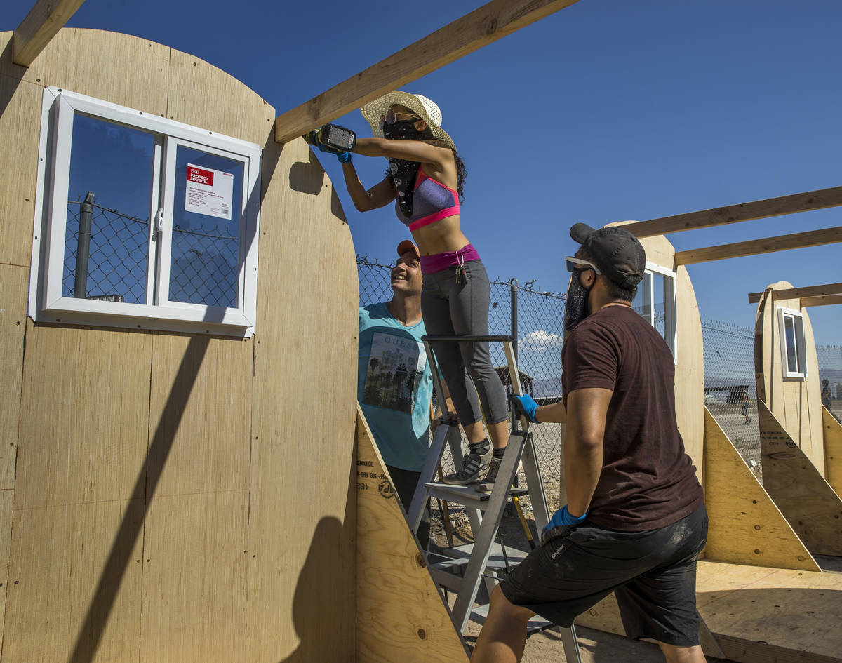 Monique Rodriguez, top left, screws down supporting beams as she and other members of Food Not ...