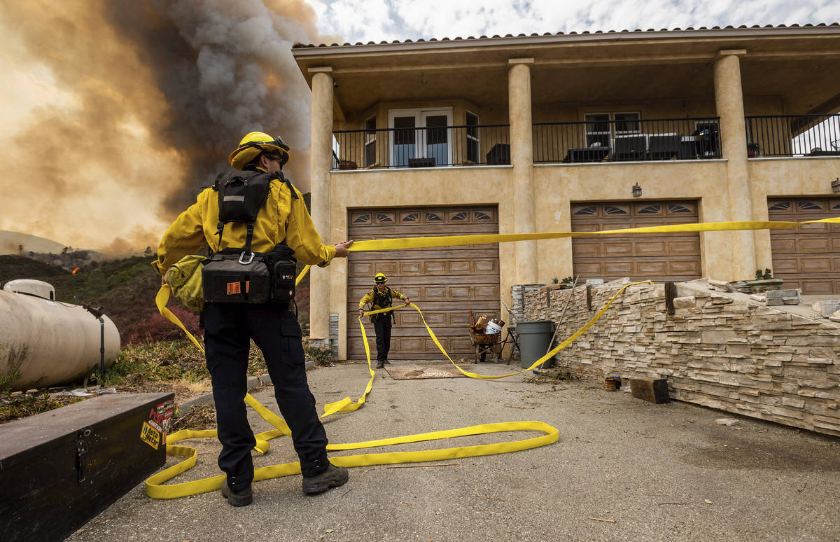 Firefighters prepare to defend a home as flames from the River Fire approaches in Salinas, Cali ...