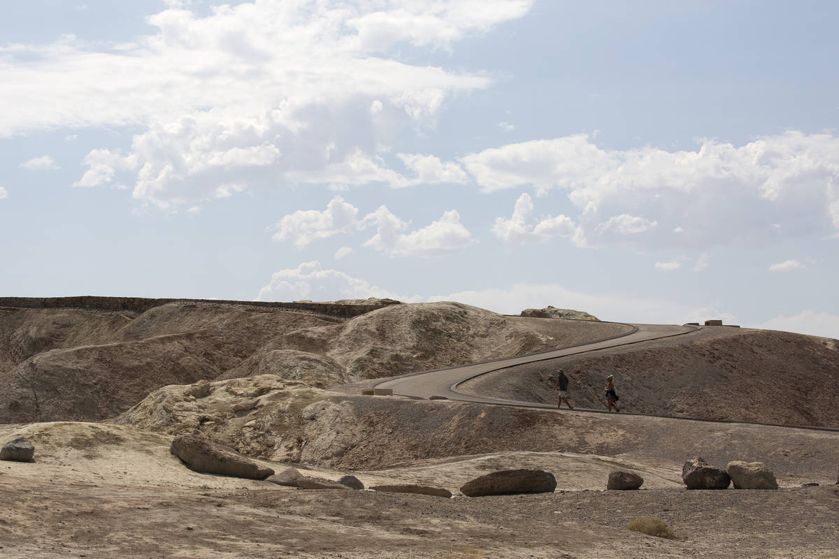 Tourists walk the road up to Zabriskie Point on a 127-degree day on Monday, Aug. 17, 2020 in De ...