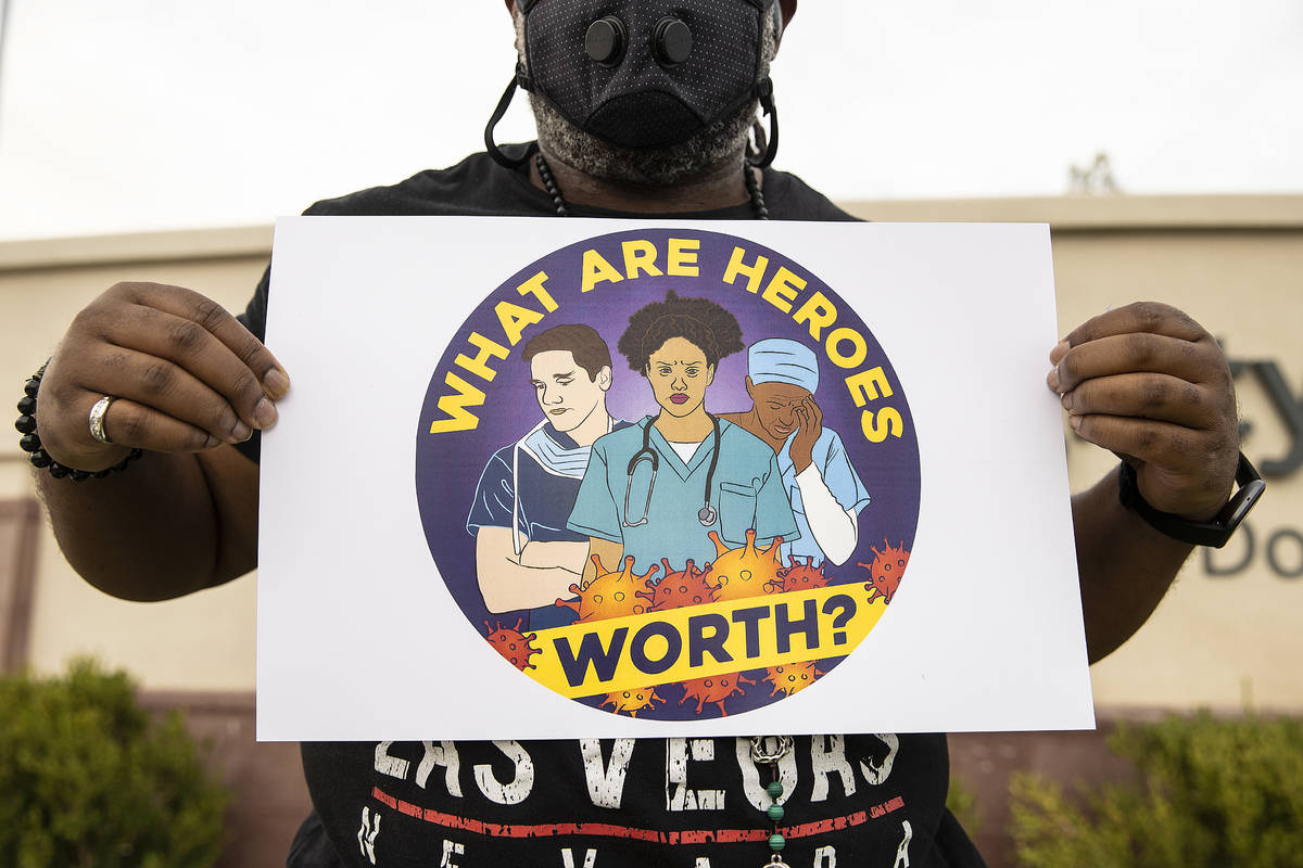 Erick Foster holds a sign during a candlelight vigil in honor of Dignity Health St. Rose Domini ...