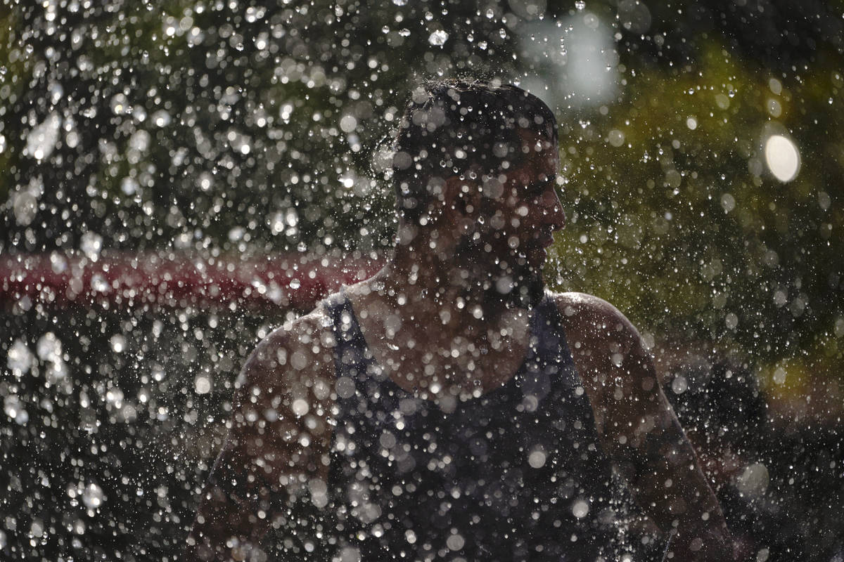Santiago Gutierrez cools off in a park Tuesday, Aug. 18, 2020, in Fountain Valley, Calif. The s ...