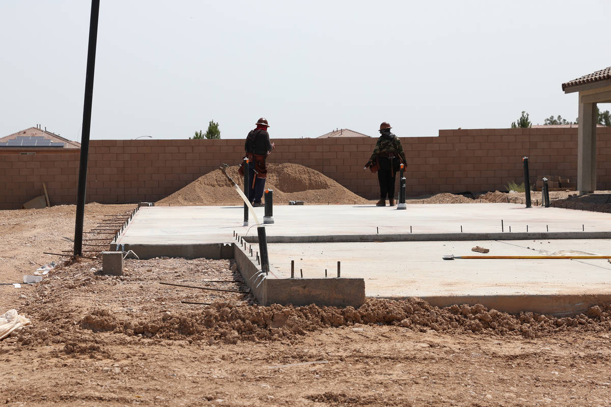 Workers stand on the slab foundation of a future home near S Fort Apache Road and W Gomer Road ...