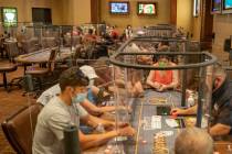 Individuals play eight-handed poker games using plexiglass dividers between the players in the ...