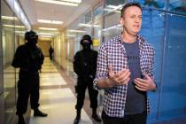 Russian opposition leader Alexei Navalny speaks to the media as policemen stand guard at the Fo ...