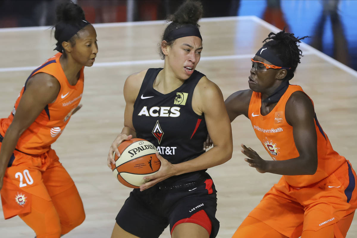 Las Vegas Aces' Dearica Hamby, center, drives between Connecticut Sun's Briann January (20) and ...