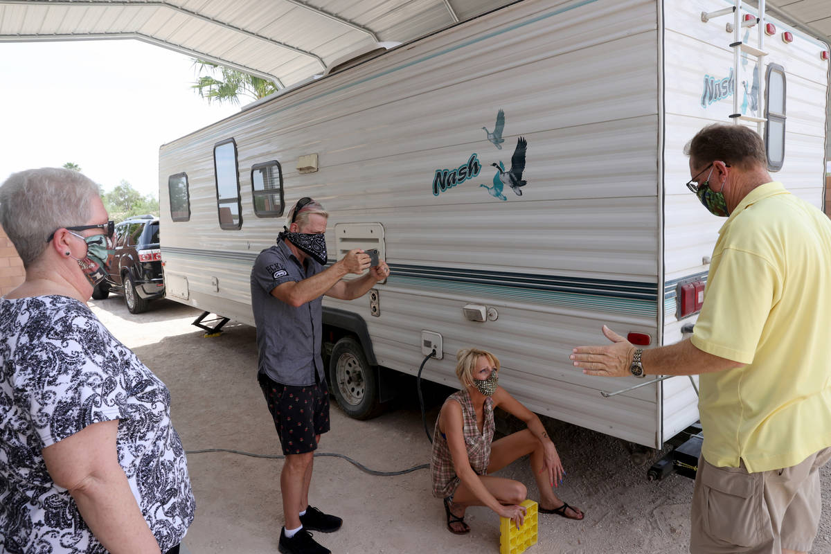 Joe Trammel, second from left, films as Don Cleveland, right, and his wife, Leslie Zak give tra ...