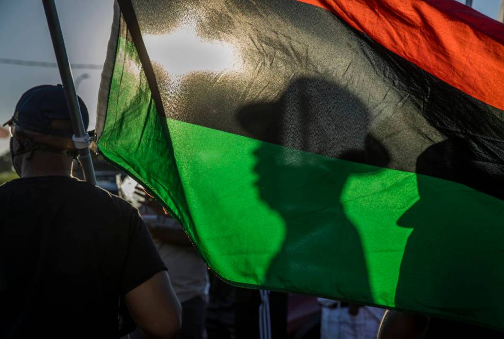 Minister Vance "Stretch" Sanders is reflected on the pan-African flag carried by New ...