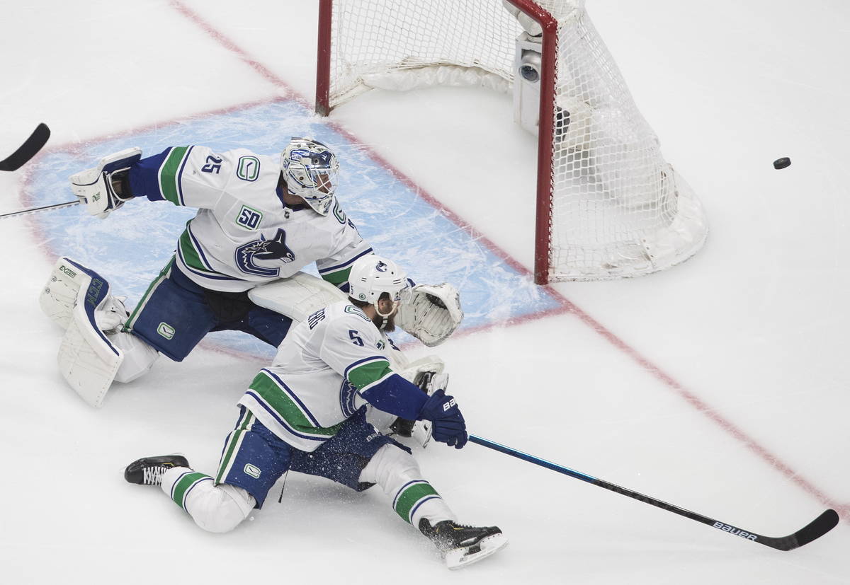 Vancouver Canucks goalie Jacob Markstrom (25) and teammate Oscar Fantenberg (5) move for the pu ...