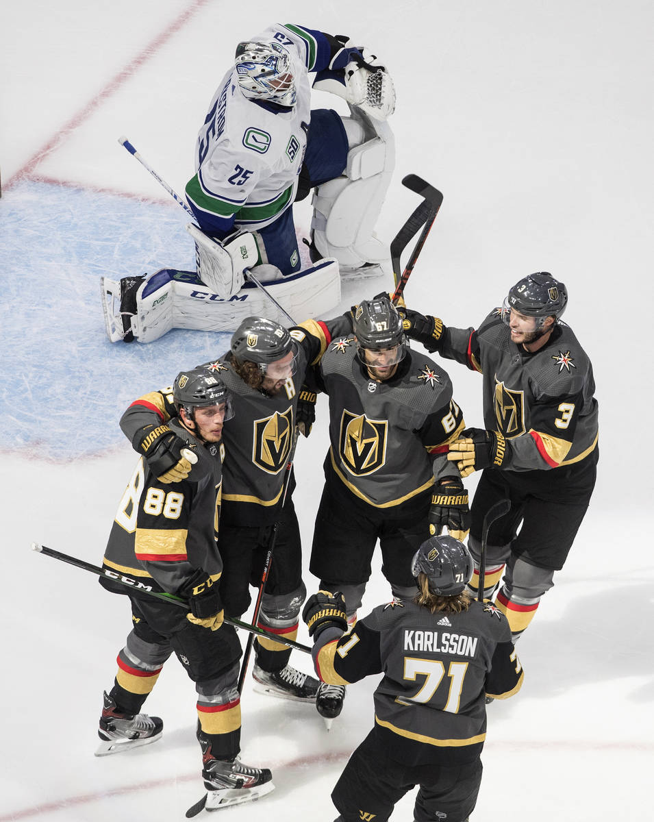 Vegas Golden Knights celebrate a goal on Vancouver Canucks goalie Jacob Markstrom, top, during ...