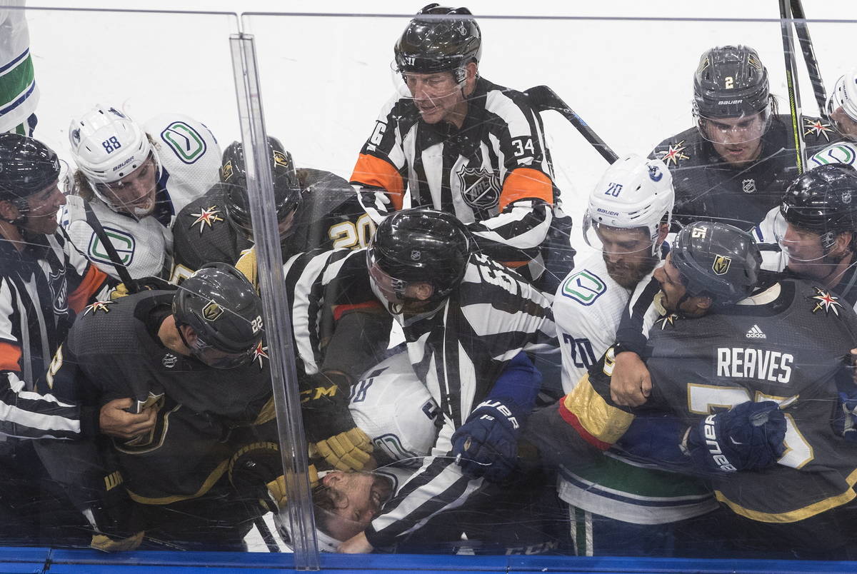Vegas Golden Knights' Nick Holden (22) fights with Vancouver Canucks' Antoine Roussel, head at ...