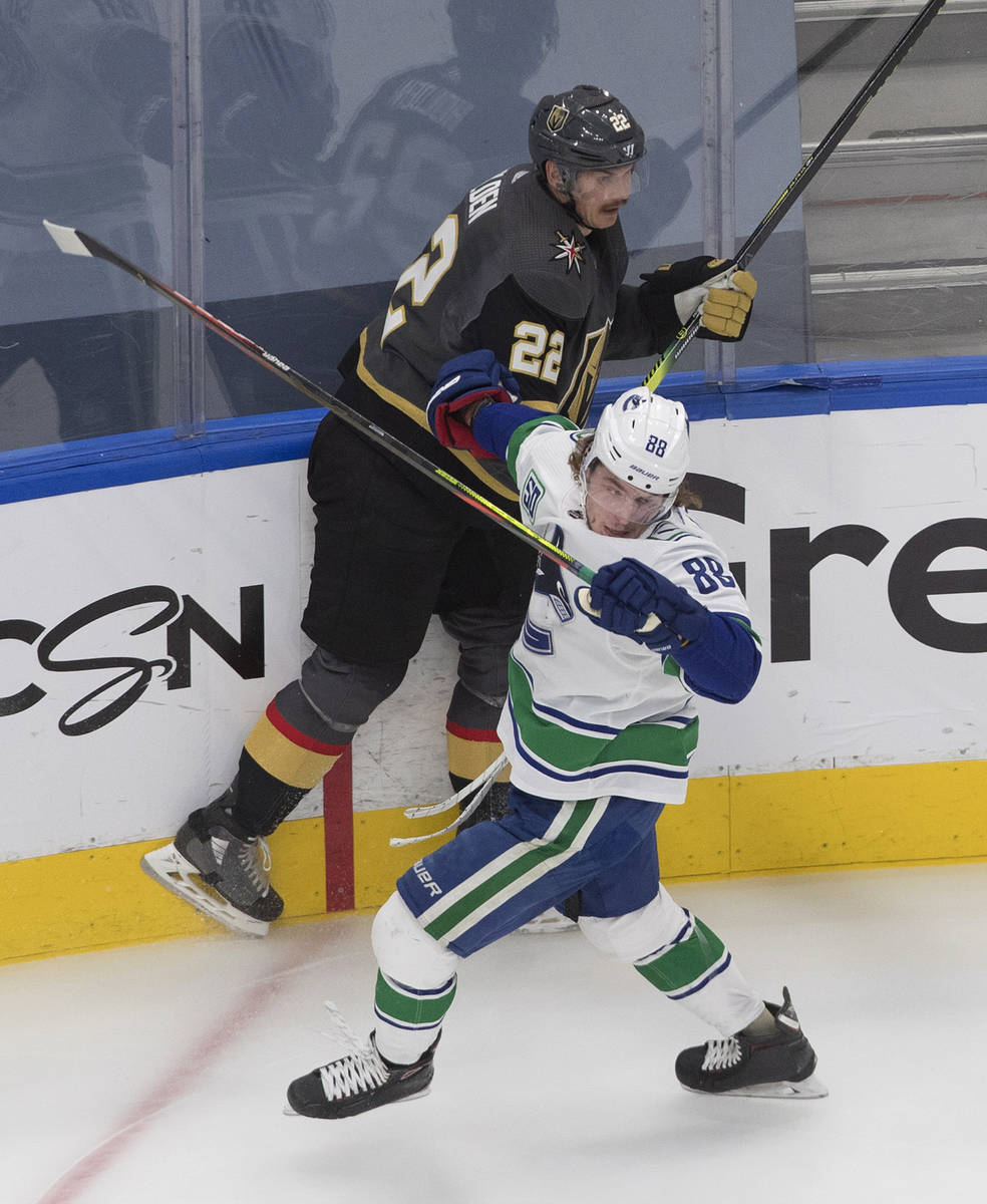 Vegas Golden Knights' Nick Holden (22) is checked by Vancouver Canucks' Adam Gaudette (88) duri ...