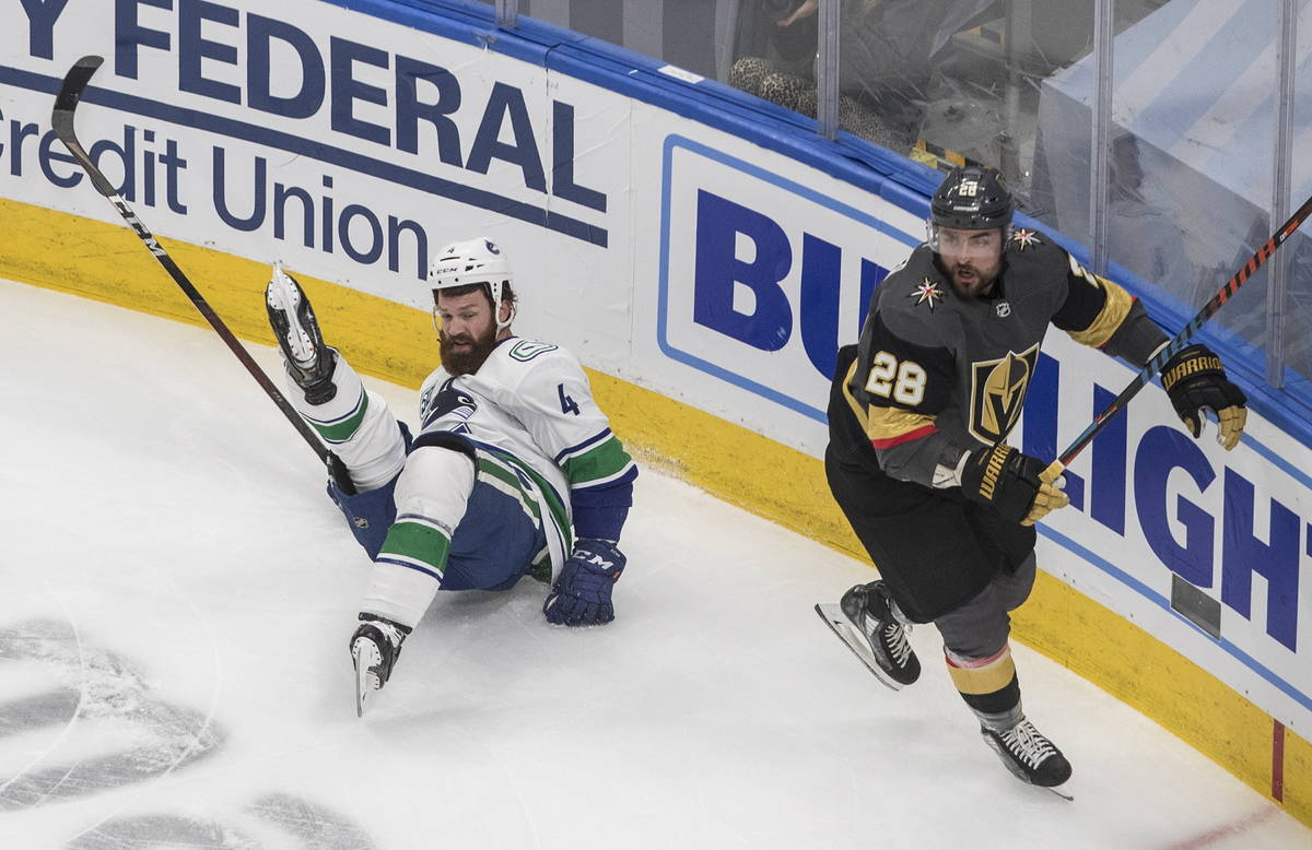 Vegas Golden Knights' William Carrier (28) checks Vancouver Canucks' Jordie Benn (4) during the ...