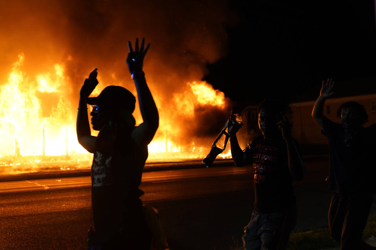 Protesters walk past police with their arms up, late Monday, Aug. 24, 2020, in Kenosha, Wis., a ...