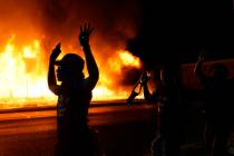 Protesters walk past police with their arms up, late Monday, Aug. 24, 2020, in Kenosha, Wis., a ...