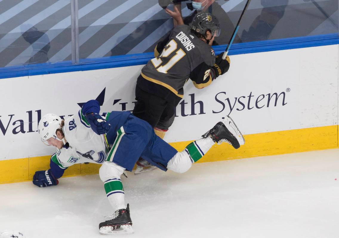 Vegas Golden Knights' Nick Cousins (21) checks Vancouver Canucks' Adam Gaudette (88) during the ...