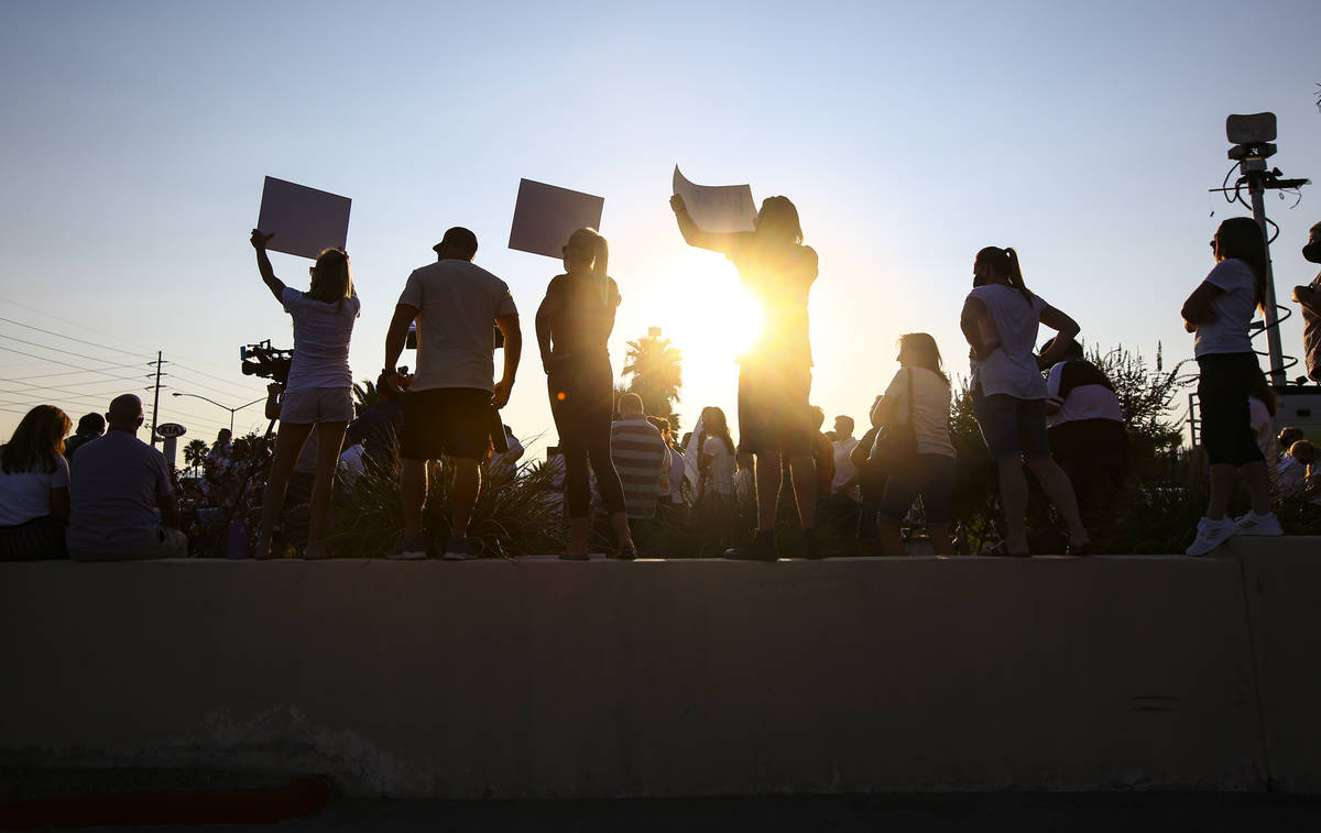 People hold up signs while participating in a demonstration in support of reopening public scho ...