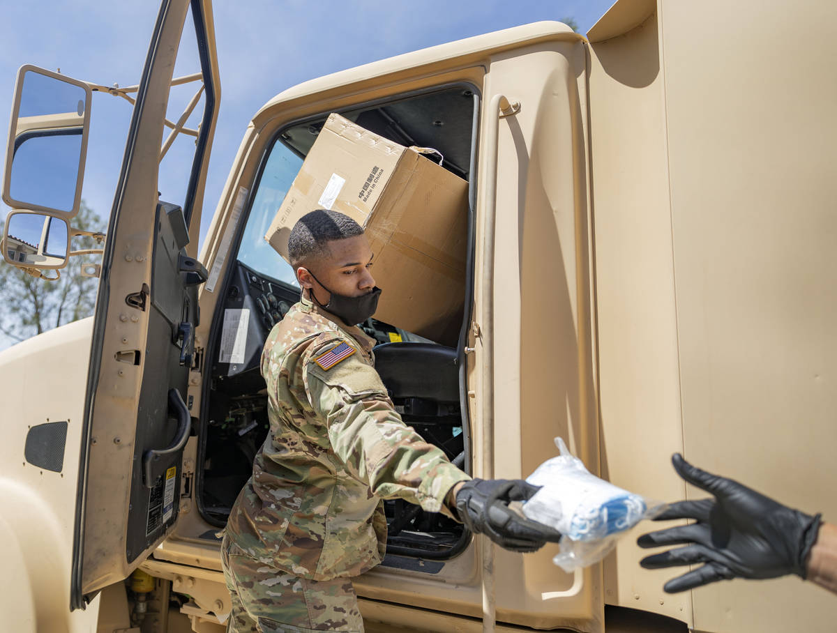 Nevada National Guard specialist Donshay Watkins hands extra surgical masks to staff of Silver ...