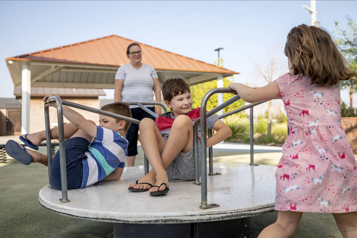 Janie Sandberg, background, watches her children Carl, 7, left, Robert, 10, center, and Clara, ...