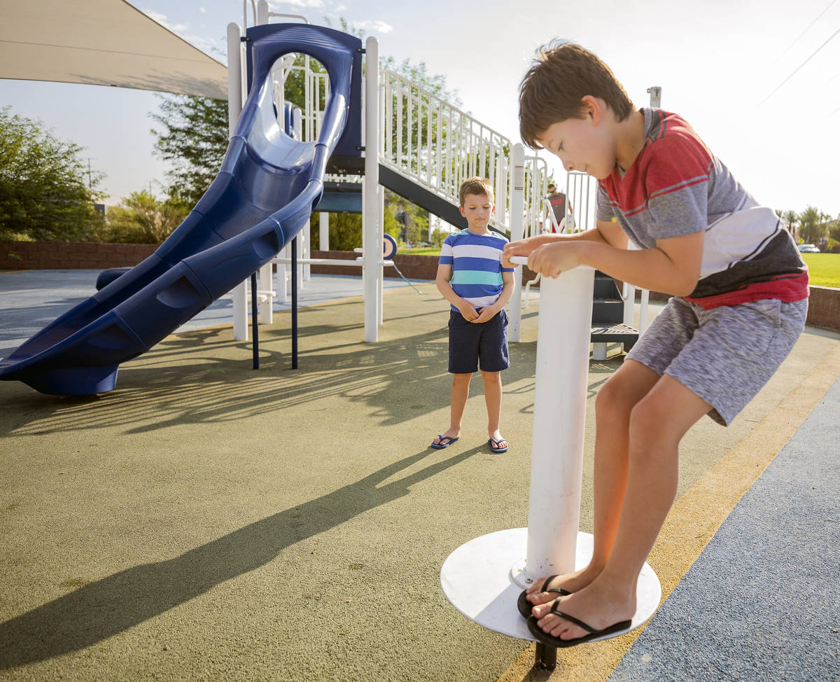 Carl Sandberg, 7, left, watches his brother Robert, 10, spin at Siena Heights Trailhead Park in ...