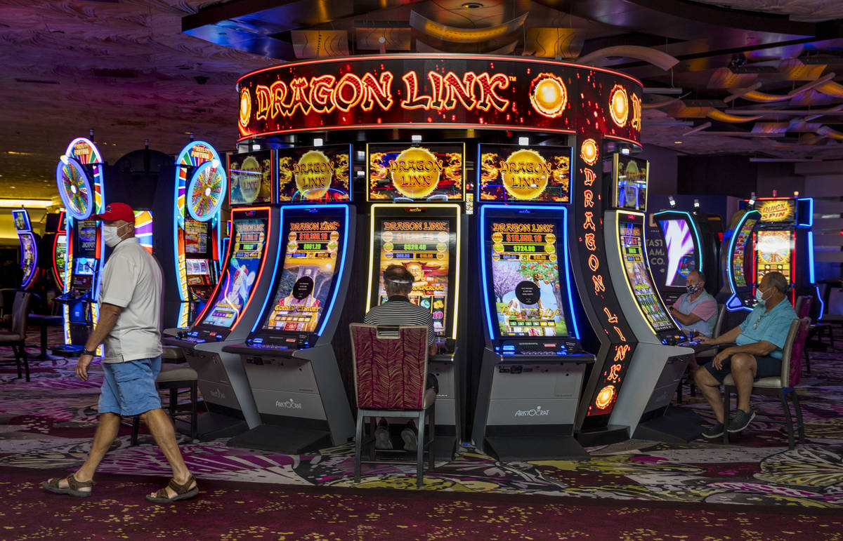 Guests play some slot machines as the Mirage reopens following a COVID