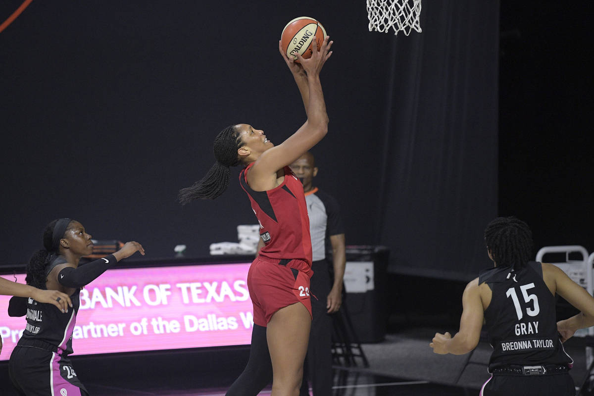 Las Vegas Aces center A'ja Wilson (22) goes up for a shot between Dallas Wings guards Arike Ogu ...