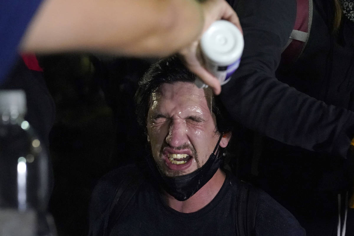 A protester is helped after police used tear gas outside the Kenosha County Courthouse late Tue ...