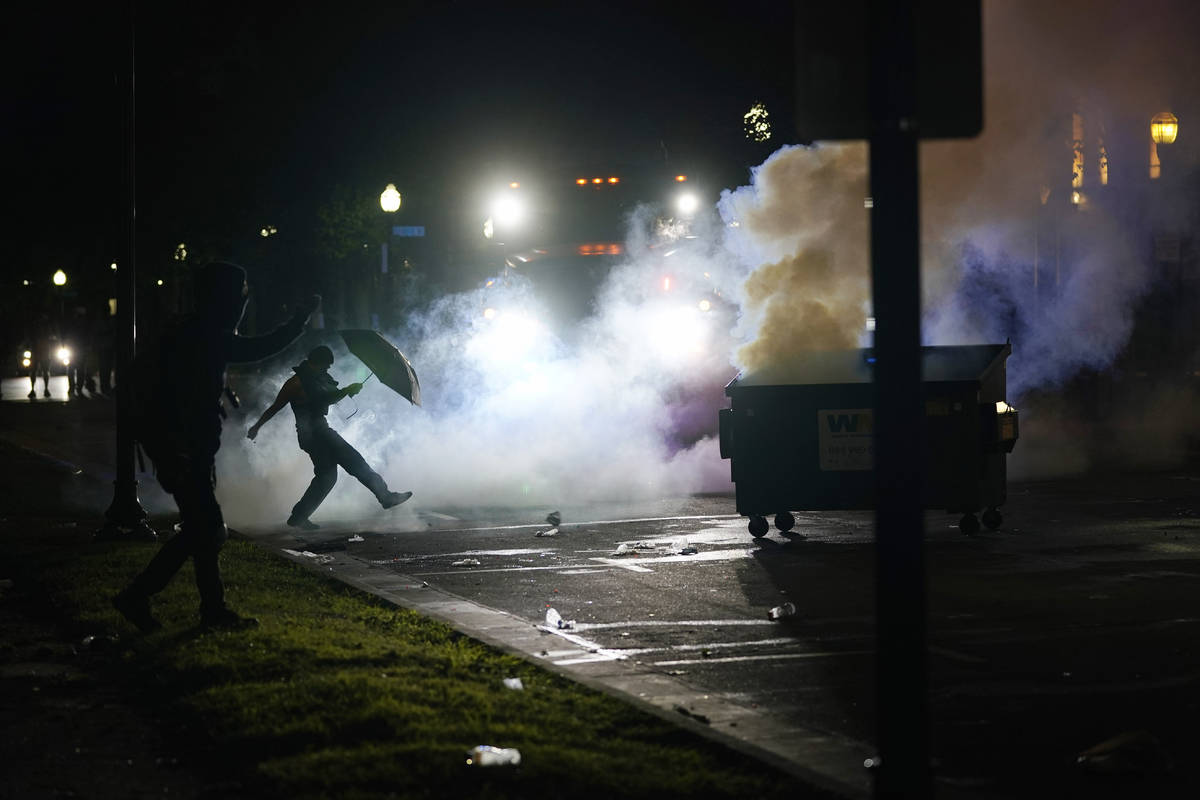 A protester kicks a smoke canister Tuesday, Aug. 25, 2020 in Kenosha, Wis. Anger over the Sunda ...